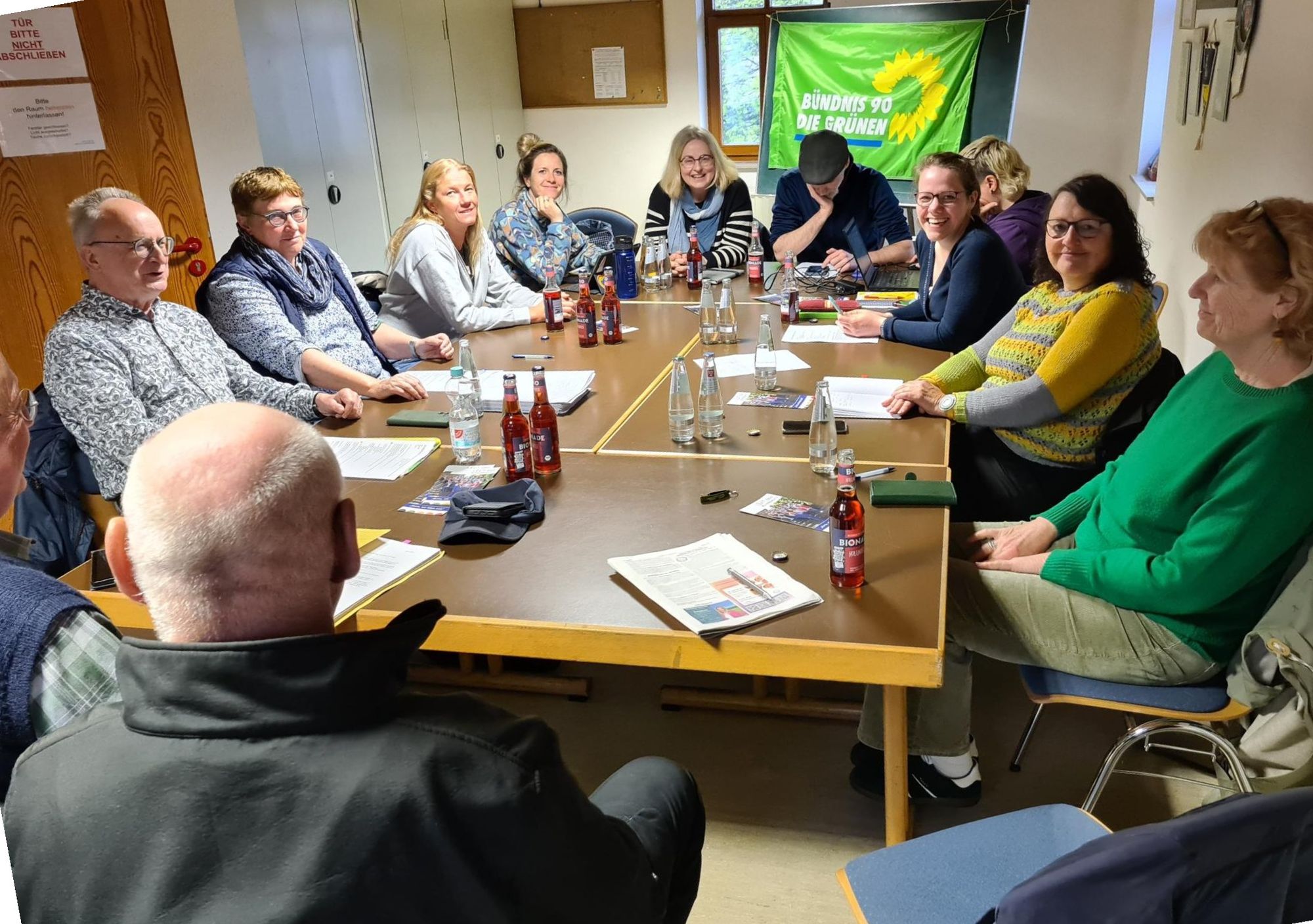 12 Personen sitzen um eine Tischgruppe, Foto einer Mitgliederversammlung
